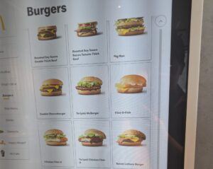 Large screen with the Japanese McDonald's menu displayed. Item of interest is the Roasted Soy Sauce Double Thick Beef burger that has a small picture of the burger next to the name.