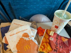 Three packets of crispy chicken patties with abstract orange designs and the label, "Shaka Shaka chicken." Next to the packets is a small bright green melon soda. 